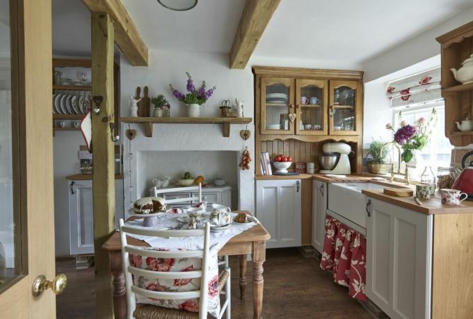Küche mit Holzschränken, Butlerspüle, Holztisch und -stühlen und roten Details