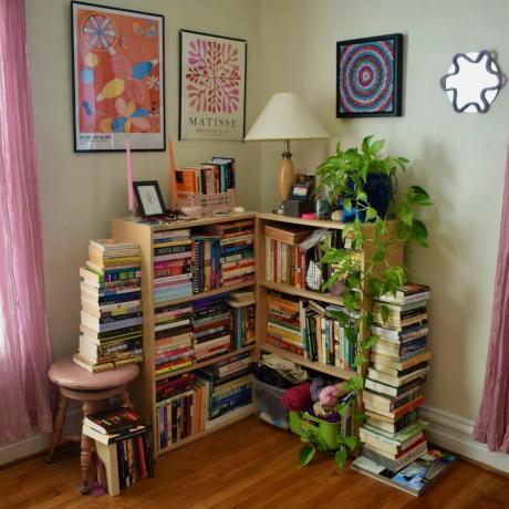 Rak buku ruang tamu kecil dengan tumpukan buku di sekelilingnya