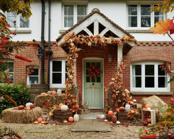 Halloween ajtódekor ötletek zöld ajtóval, őszi koszorúval, szénával, sütőtökökkel