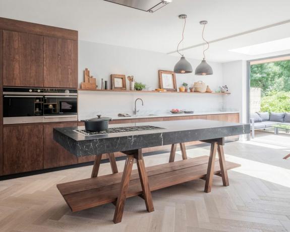 una moderna cucina in legno scuro con isola autoportante con lastra di marmo di Naked Kitchens