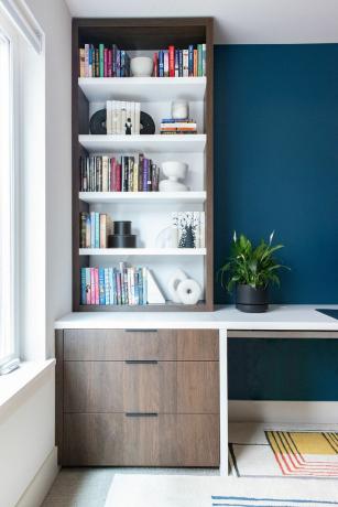 Стилизована дрвена полица за књиге у плаво обојеној соби