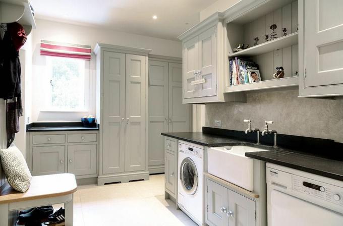 Stort vaskerom med vask i Belfast, grå lagringsenheter i shaker -stil, åpne hyller, vaskemaskin og tørketrommel som en ide for å designe et vaskerom