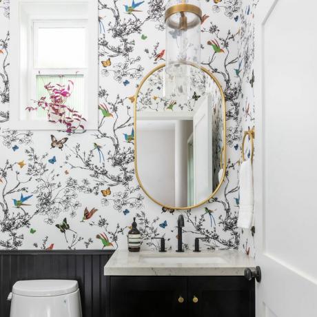 Vonios kambarys su praustuvu, tapetuota siena ir aukso rėmo veidrodžiu
