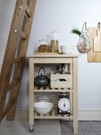 Un carrello in legno Ikea come ripostiglio con utensili da cucina sotto una scala