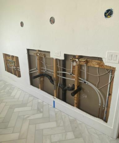 बेज दीवार पेंट सजावट, हेरिंगबोन फर्श सजावट और क्वार्ट्ज काउंटरटॉप और सैनिटरीवेयर प्लंबिंग के लिए तैयार जगह के साथ एक आधुनिक बाथरूम