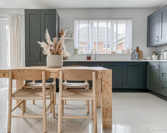 mėlyna virtuvė su baltais stalviršiais ir natūralaus medžio kilimėliu