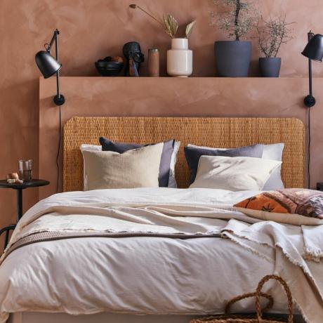 Terrakotta -seinät hyllyllä neutraalin värisen sängyn päällä