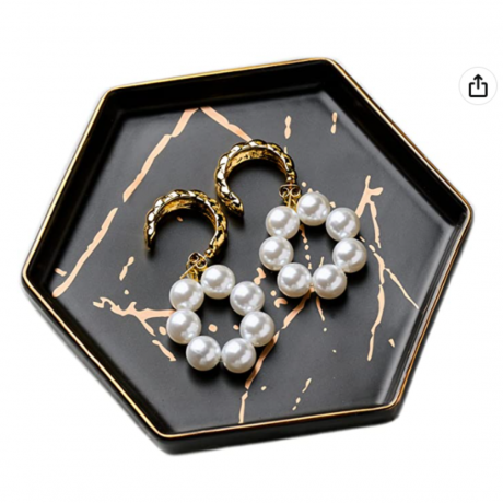 Un joyero geométrico con aretes de perlas.