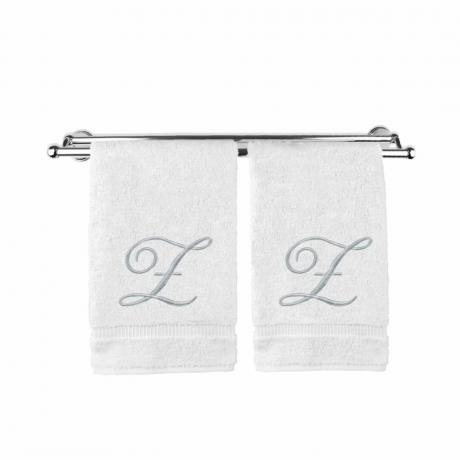 Du balti monograminiai rankšluosčiai ant rankšluosčių laikiklio