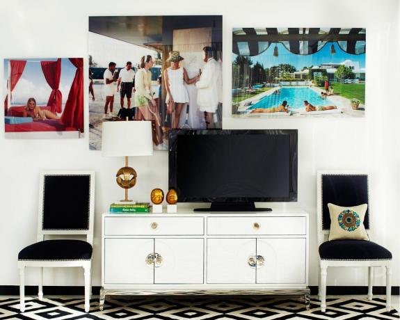 Un soggiorno con galleria a parete, consolle bianca e TV