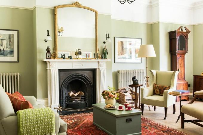 salon vert avec cheminée, fauteuils et miroir