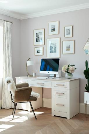 klasisks mājas biroja galds ar galerijas sienu gaiši rozā sienām un koka grīdu