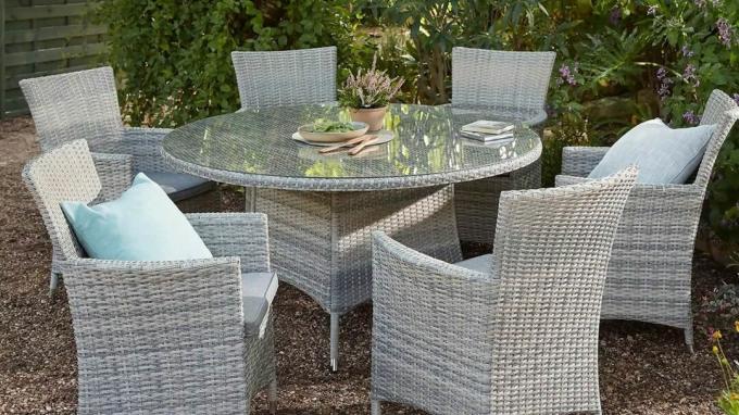 Kruhový záhradný stôl a ratanová záhradná stolička položená na štrkovej terase