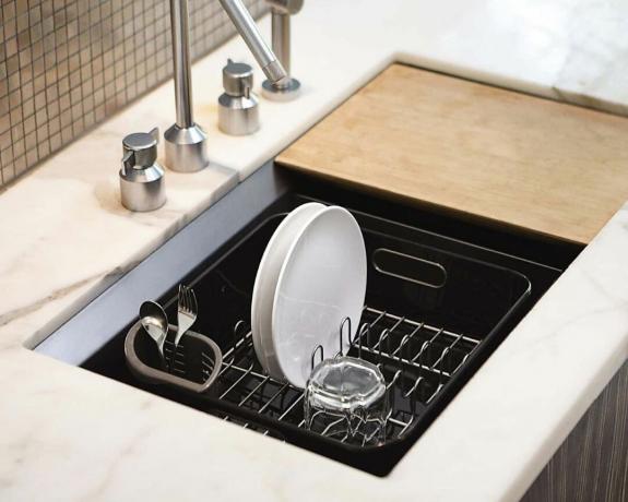 обикновен черен съд за миене в мивка с две чинии и едно стъкло за сушене вътре