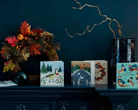 Una repisa de chimenea de Navidad con tarjetas de Navidad y una corona