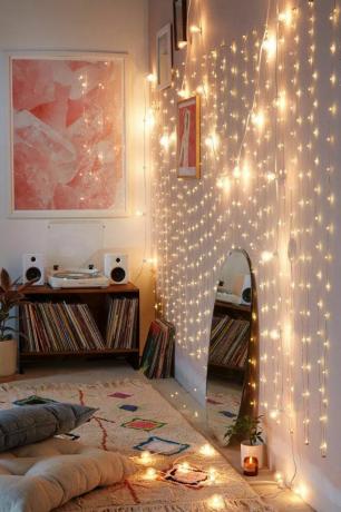 Yuvarlak ayna, etnik tarzda halı ve plak çalar ile sıcak LED ışıklı bir yatak odası