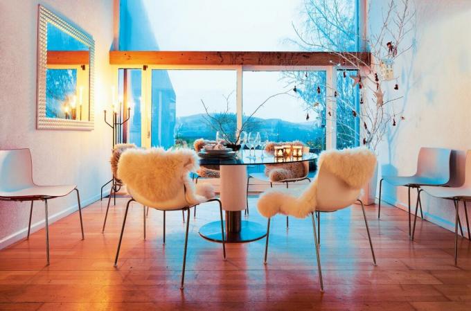 Sala de jantar em estilo escandinavo com uma grande janela panorâmica ao anoitecer