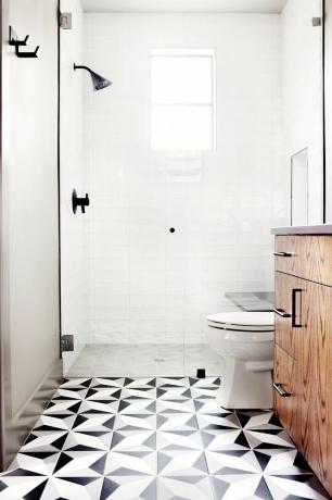 moderna dušas telpa ar baltām metro flīzēm un vienkrāsainu grīdu