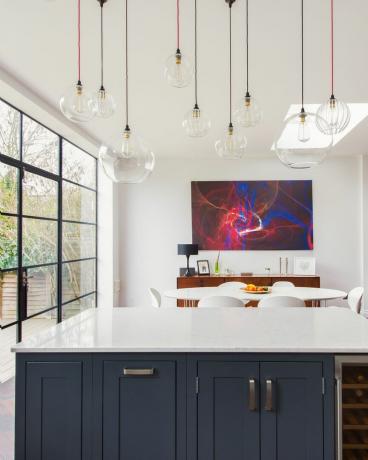 ห้องครัวแบบเปิดโล่งพร้อมโคมไฟระย้าและการตกแต่งภายในสีน้ำเงินโดย fritz fryer