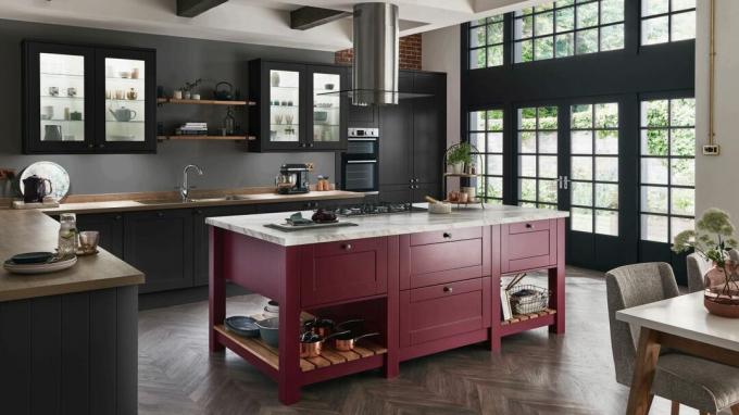 Tmavě šedá kuchyně s červeným kuchyňským ostrůvkem, kovovými rámovými okny a tvarem L.