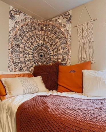 Guļamistaba ar krāsainu gobelēnu pie sienas ar gaismas virtenēm