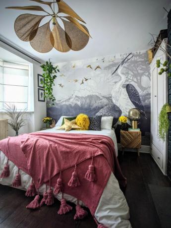 O mural do quarto do guindaste enquadra a cama com um lance de borla rosa choque e detalhes em amarelo