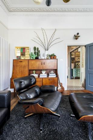 De woonkamer met een grote leren en houten ligstoel en vintage houten dressoir