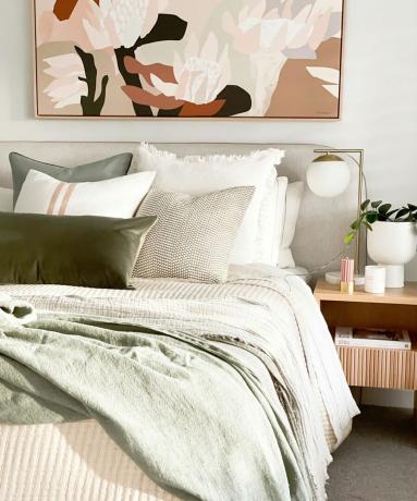 dubbelsäng i sovrum med fräscha sängkläder, nattduksbord och abstrakt konsttryck