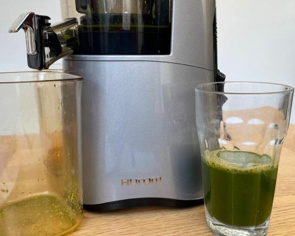 מיץ ירקות ירוקים בכוס עשוי באמצעות מכשיר המסחטה האיטית Hurom H-AA
