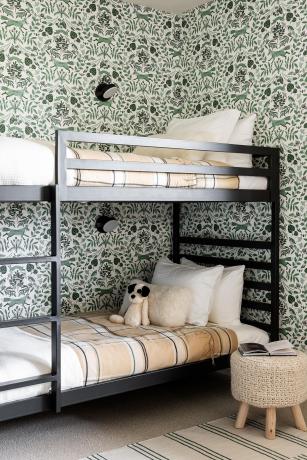 Зелена позадина са ботаничким штампом у дечијој спаваћој соби са дрвеним црно обојеним креветима и слатким плишаним животињама