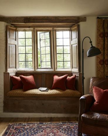 lango sėdynė priešais tradicinį langą Cotswold namuose