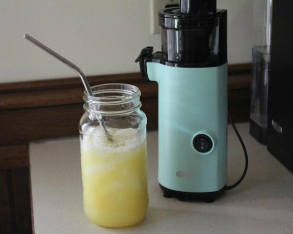 Ein frisch zubereiteter Apfel-Ananas-Saft in einem Marmeladenglas aus Glas mit Metallstrohhalm mit dem kleinen Küchengerät Dash Compact Power Juicer