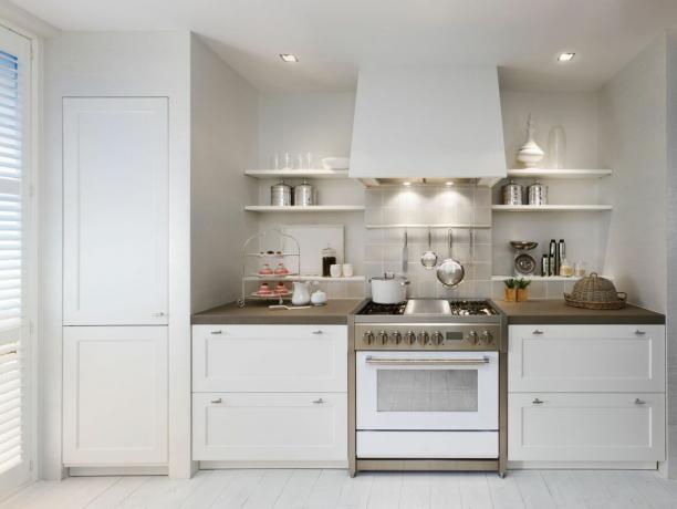 hvitt kjøkken med store lagringsenheter og komfyr av stål