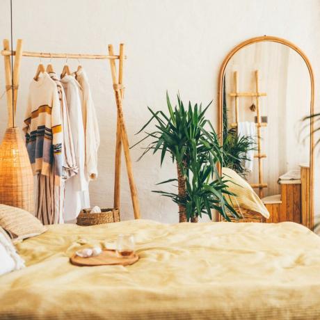 boho magamistuba peegelkollase voodikatte, riidenagi ja taimega