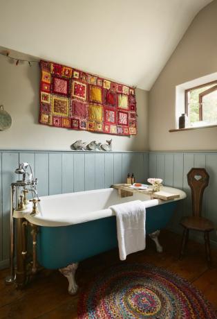 blå fritstående badekar på badeværelse med gobelin og panel