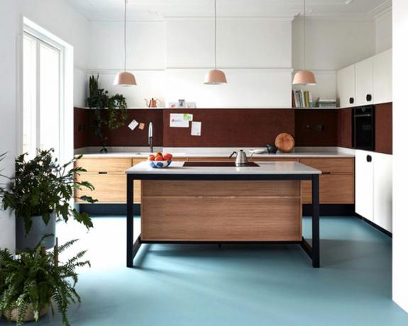 Puidust ja metallist kontrastne köögisaar, mille kohal on riputatud kolm ripatsit ja sinine põrand