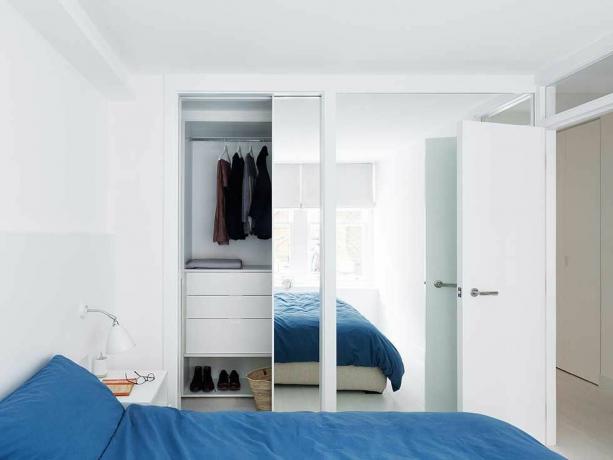 غرفة نوم لندن باللون الأبيض المسطح ، فراش أزرق مفصل في خزانة الملابس