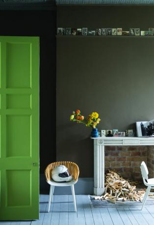 Värvitud põrandalauad rohelises ruumis, puidust värvitud ukse, telliskamina ja väikese aktsenditooliga