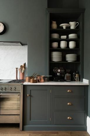 una piccola idea di cucina in grigio antracite scuro con accenti dorati e parete colorata abbinata con mobili aperti e fornello in acciaio inossidabile