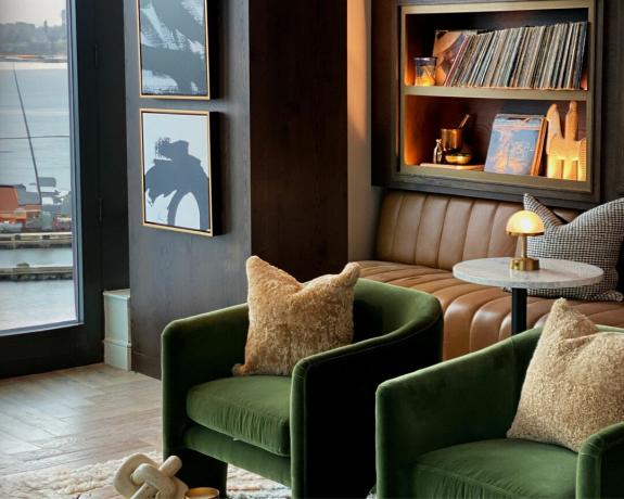 הסלון של Lauren Jayne Design עם כיסאות ירוקים, ספסל עור ואוסף ויניל