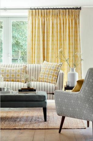 Salon w stonowanej żółtej kolorystyce z sofami w paski i wzorzystymi poduszkami jako przykład łączenia wzorów i nadruków we wnętrzach autorstwa vanessy arbunthnott