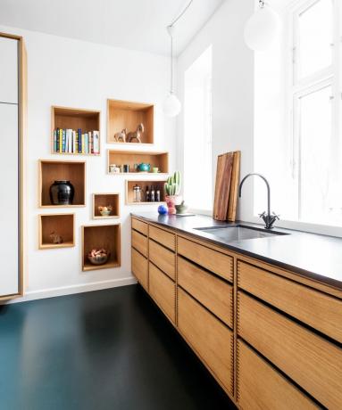 Una cocina moderna con gabinetes de madera natural y pisos de linóleo verde oscuro