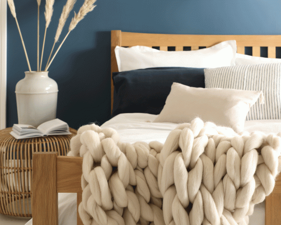 豪華なベッドと分厚いニットスローを備えた寝室の青い壁
