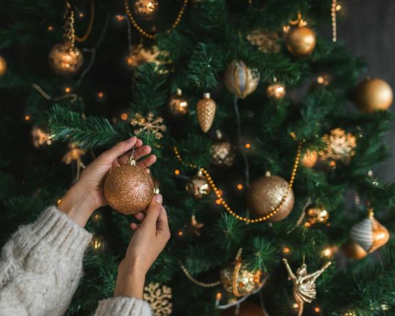 žena dodaje božićne kuglice na drvce