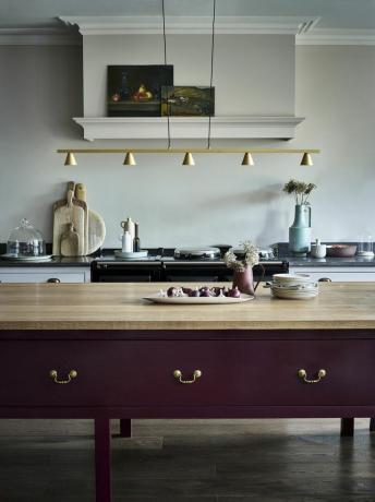 серая кухня с отдельно стоящим кухонным островом, окрашенным в фиолетовый цвет, подвесное освещение, AGA, произведение искусства