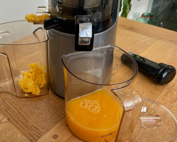 Hurom H-AA yavaş meyve sıkacağında portakal sıkma işleminin ortası, sürahideki meyve suyu verimi ile gösterilen posa ekstraksiyonu