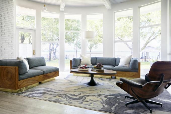 nasłoneczniony pokój z dużym dywanem oraz nowoczesnymi sofami i fotelem