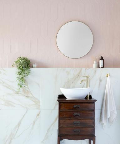 Раковина в ванной комнате со светло-розовой плиткой на стенах и мраморной плиткой.