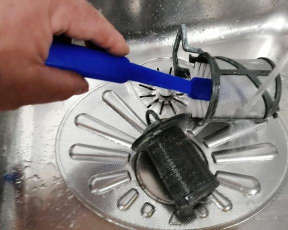 Een vaatwasserfilter wordt gereinigd met een borstel