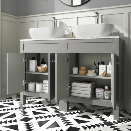 doppio lavabo in grigio con ante aperte che mostrano lo stoccaggio, pavimento piastrellato bianco e nero